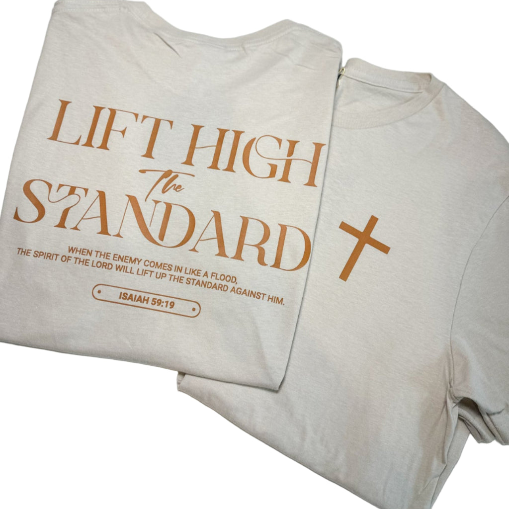 Beige t-shirt with 'Lift High the Standard' text and cross design on a white background